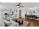 Open-concept living room featuring hardwood floors, ceiling fan, a large gray sectional sofa, and views into the kitchen and dining room at 199 High Woods Rdg, Chapel Hill, NC 27517