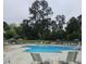 Inviting community pool area with ample seating and umbrellas surrounded by mature trees for shade at 2055 Eva Pearl Dr, Apex, NC 27502