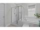 Bright bathroom featuring glass enclosed shower, and soaking tub below a large window at 3310 Mission Olive Pl, New Hill, NC 27562