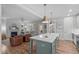 A kitchen island with light-colored stone top and undermount sink overlooks a living room with a fireplace at 3310 Mission Olive Pl, New Hill, NC 27562