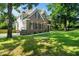 A side view of the brick home featuring a sprawling green lawn with mature tree shade and a garage at 3811 Cottonwood Dr, Durham, NC 27705