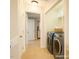 Bright laundry room with gray front-loading washer and dryer with white shelving and towels on the top shelf at 401 Holly Thorn Trce, Holly Springs, NC 27540