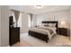 Well-lit main bedroom featuring a tray ceiling, neutral walls and curtains, and traditional furnishings at 401 Holly Thorn Trce, Holly Springs, NC 27540