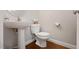 Compact powder room featuring a pedestal sink, toilet, and hardwood floors offering functionality in a small space at 401 Holly Thorn Trce, Holly Springs, NC 27540