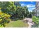 Landscaped backyard with a lush lawn, mature trees, flowering shrubs, and a brick patio with an arbor at 413 Westfalen Dr, Cary, NC 27519
