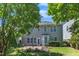 Landscaped backyard with a brick patio, arbor, flowering trees, and neutral siding with white trim windows at 413 Westfalen Dr, Cary, NC 27519