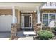 Inviting front porch with stone pillars, a dark brown door, and a sidelight at 413 Westfalen Dr, Cary, NC 27519