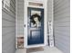 Close-up of the front door with a welcome wreath, smart lock, and a charming welcome mat on the porch at 440 Bramble Ln, Clayton, NC 27527