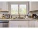 A modern kitchen sink area with white cabinets and a view of the outdoors at 460 Dickens Dr, Raleigh, NC 27610