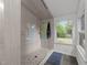 Bright bathroom featuring walk-in shower, gray tile walls, pebble floor, and a window with a verdant view at 4812 Latimer Rd, Raleigh, NC 27609