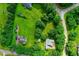 Aerial view of home surrounded by trees and well-manicured lawn featuring gray roof, backyard shed, and long driveway at 5309 Meadow Field Dr, Mebane, NC 27302