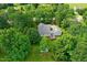 Aerial view of property showing well-manicured lawn, mature trees, gray roof, and outdoor seating area at 5309 Meadow Field Dr, Mebane, NC 27302
