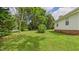 Side yard with lush green grass, mature trees, and a well-maintained exterior at 5309 Meadow Field Dr, Mebane, NC 27302
