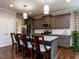 Gourmet kitchen island has stone countertops and four bar stools, complemented with pendant lighting at 604 Doddington Dr, Rolesville, NC 27571