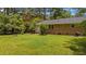 Spacious backyard with a well-maintained lawn featuring mature trees and an exterior brick wall of the home at 625 Powell Dr, Rocky Mount, NC 27803