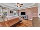 Bedroom featuring a tray ceiling, brick accent wall, hardwood floors, and neutral decor at 71 Smithsanders Ct, Smithfield, NC 27577