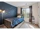 Comfortable carpeted bedroom with blue accent wall, window, and storage under the bed at 9504 Anson Grove Lane Ln, Raleigh, NC 27615