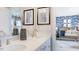 Bright bathroom with double sinks and a view into a charming baby room with blue patterned wallpaper and wooden crib at 121 Seagraves Creek Ln, Holly Springs, NC 27540