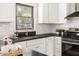 Modern kitchen with white cabinetry, black countertops, and stainless steel appliances at 16 Cedar Hill Dr, Durham, NC 27713