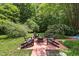 Cozy outdoor space with Adirondack chairs surrounding a fire pit and landscaped with mature trees at 213 Chimeneas Pl, Chapel Hill, NC 27517