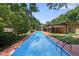 A backyard view of a long rectangular pool surrounded by trees, landscaping, and a patio area with house in background at 213 Chimeneas Pl, Chapel Hill, NC 27517