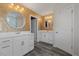 Dual vanity bathroom featuring white cabinets, mirrors, sconce lighting, and attractive wallpaper at 2713 Jazzy St, New Hill, NC 27562