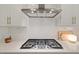 Close up of a modern gas cooktop with stainless steel vent hood and subway tile backsplash at 2713 Jazzy St, New Hill, NC 27562