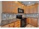 Well-equipped kitchen with wood cabinets, black appliances, and granite countertops at 300 Williamston Ridge Dr, Youngsville, NC 27596