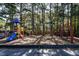 Community playground featuring a colorful playset and swing set surrounded by pine trees at 3045 Creek Moss Ave, Wake Forest, NC 27587