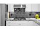 Kitchen close up featuring a stainless range hood, black backsplash, granite counter, and gas cooktop at 3604 Thorndike Dr, Wake Forest, NC 27587