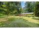Lush green backyard with mature trees, a wooden deck, and home exterior at 420 Lipscomb Grove Church Rd, Hillsborough, NC 27278