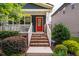 A welcoming front porch with brick stairs, a white railing, an inviting red door and manicured landscaping at 426 Granite Mill Blvd, Chapel Hill, NC 27516