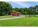 Charming red barn with white trim, complemented by a lush green lawn and gravel driveway at 633 Fleming Rd, Youngsville, NC 27596
