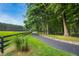 Scenic view of a blacktop driveway lined with trees, leading to a green field at 633 Fleming Rd, Youngsville, NC 27596