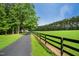 Long paved driveway leading through a verdant landscape and past a black fence at 633 Fleming Rd, Youngsville, NC 27596
