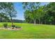 Lush green lawn with a flowerbed beneath a tree, on a sunny day at 633 Fleming Rd, Youngsville, NC 27596