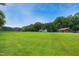Expansive green field with trees, surrounded by a black wooden fence on a sunny day at 633 Fleming Rd, Youngsville, NC 27596