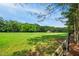 Scenic view of a sprawling green field with trees and a black fence under a blue sky at 633 Fleming Rd, Youngsville, NC 27596