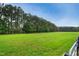 Expansive grass field, lined with mature pine trees and a black wooden fence at 633 Fleming Rd, Youngsville, NC 27596