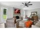Bright living room featuring a brick fireplace, large windows, ceiling fan, and comfortable seating at 633 Fleming Rd, Youngsville, NC 27596