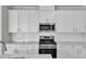 Close-up of a modern kitchen with stainless steel appliances and white cabinetry at 6549 Tremolo Trl, Raleigh, NC 27616