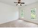 Neutral bedroom featuring plush carpeting, two windows that let in natural light, and a ceiling fan at 709 Skymont Dr, Holly Springs, NC 27540
