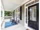 Inviting front porch with rocking chairs and a decorative front door and stylish blue striped rug at 709 Skymont Dr, Holly Springs, NC 27540