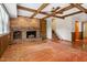 Living room featuring a brick fireplace, wood floors, and exposed beam ceiling at 7620 Harps Mill Rd, Raleigh, NC 27615