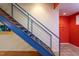 Modern staircase with blue railing and wooden steps, next to red wall and tiled floor at 820 Runnymede Rd Rd, Raleigh, NC 27607