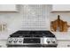 Close-up of a stainless steel gas range cooktop with decorative backsplash and modern countertops at 947 Manchester Dr, Cary, NC 27511