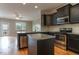 Modern kitchen with granite countertops, stainless steel appliances, black cabinets, and a functional island, open to the living area at 996 Tender Dr, Apex, NC 27502