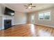 Spacious living room with hardwood floors, fireplace, a ceiling fan, and a glass door providing access to the outdoor space at 996 Tender Dr, Apex, NC 27502