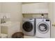 Well-lit laundry room with white cabinets, stainless steel washer and dryer units, and a utility sink at 1016 Pasture View Ln, Raleigh, NC 27603
