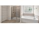 Modern bathroom featuring a tiled shower, a tub, and large window with backyard views at 1124 Dartford Green Pl, Wake Forest, NC 27587